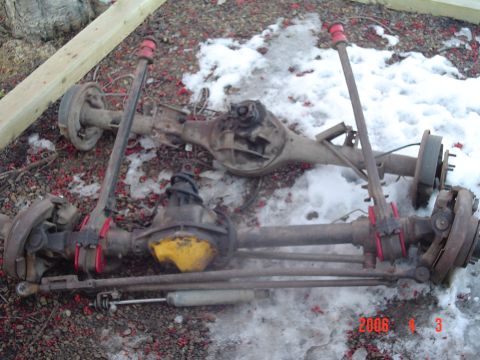 1995 Ford Bronco - Disassembled vehicle axles are laid out on the ground, showing parts like differential covers and suspension components.