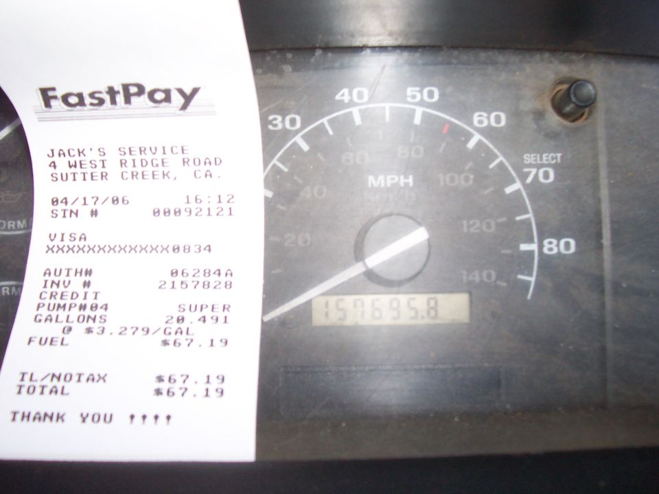 2006 fuel receipt for 20.491 gallons held against a Ford speedometer showing 157,695.8 miles