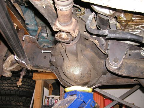 1984 Ford Bronco - Underside view of a vehicle's rear differential and driveshaft, supported by a jack.