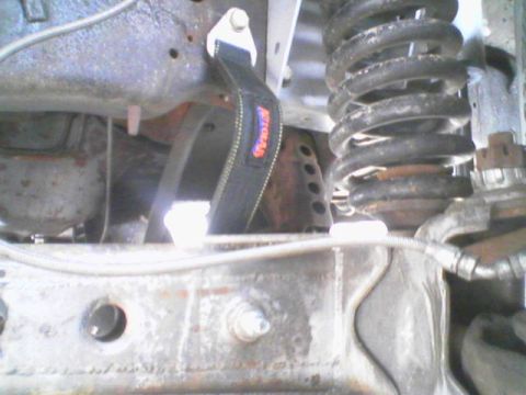1984 Ford Bronco - Close-up of the undercarriage, highlighting the suspension system and a tow strap with visible branding.