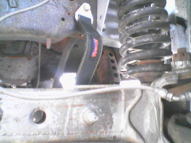 Undercarriage view showing suspension components and a black tow strap with orange lettering