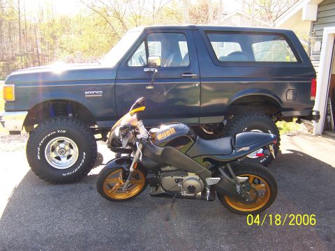 1987 Ford Bronco - A 1987 Ford Bronco and a Buell motorcycle are parked side-by-side outdoors.
