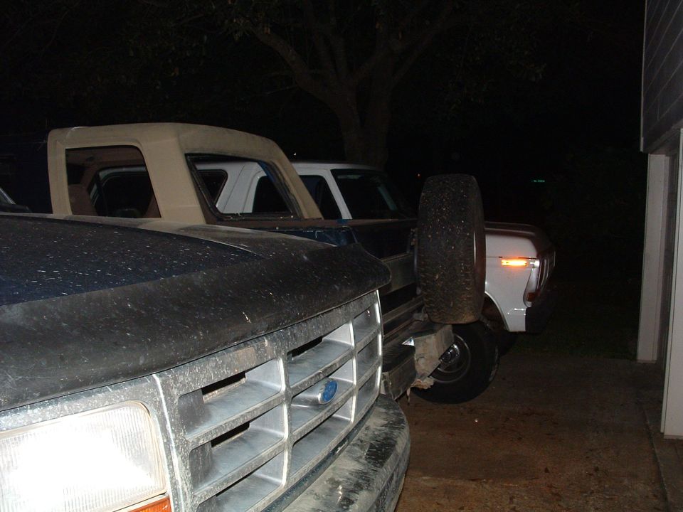 1993 Ford Bronco and another Ford truck parked outdoors at night