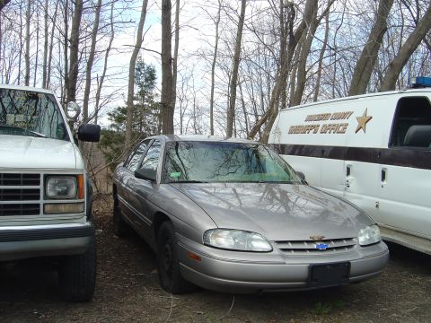 2001 Ford Crown Victoria - A Chevrolet Lumina sedan is parked next to a white truck and a Worcester County Sheriff's Office van.