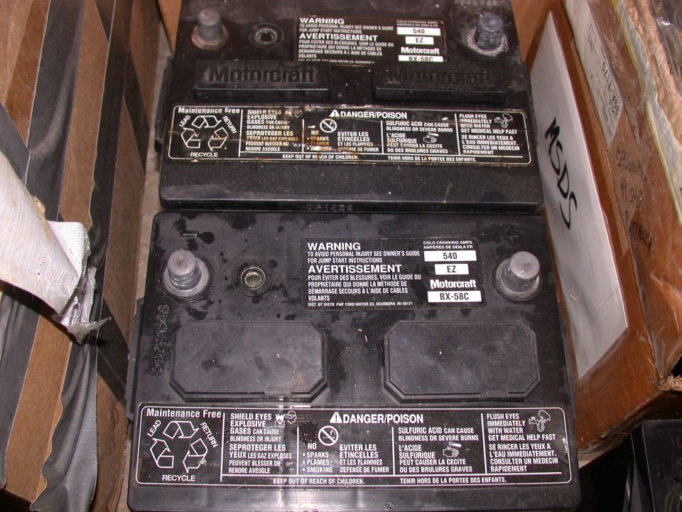 Two black Motorcraft BX-58C 540 CCA car batteries with warning labels, sitting in cardboard boxes