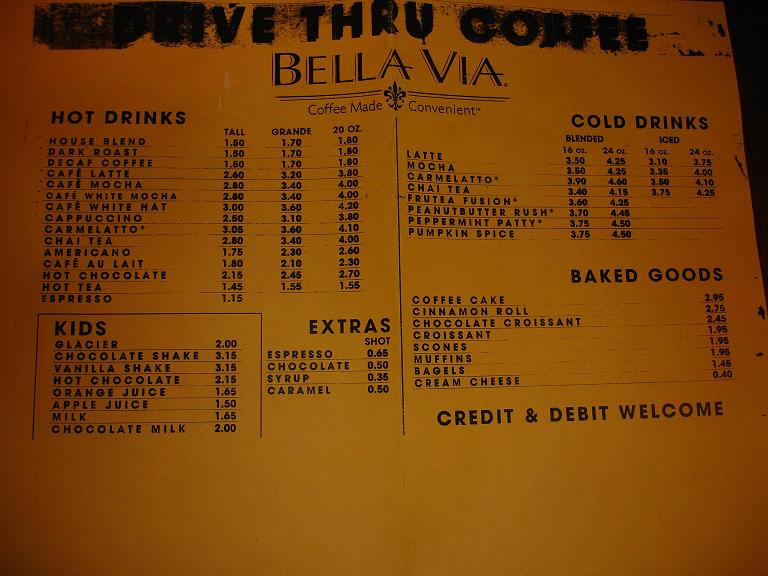 Yellow menu for Bella Via coffee shop with hot drinks, cold drinks, kids' drinks, extras, and baked goods listed
