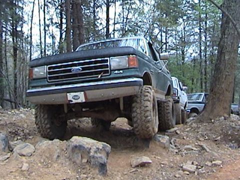 1996 Ford Bronco - This lifted Ford F-Series truck navigates a challenging off-road course with other vehicles following.