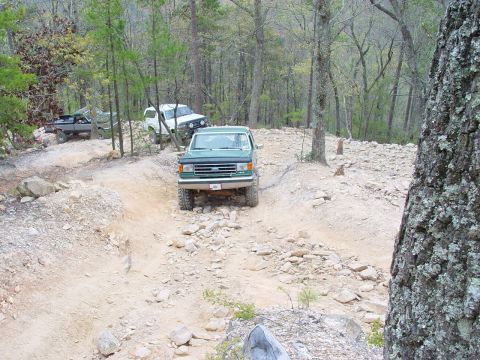 1996 Ford Bronco - Green 1996 Ford F-150 pickup truck on a rocky trail with other vehicles behind it.