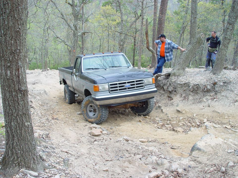 Ford F-Series pickup truck on a dirt trail with two guys nearby