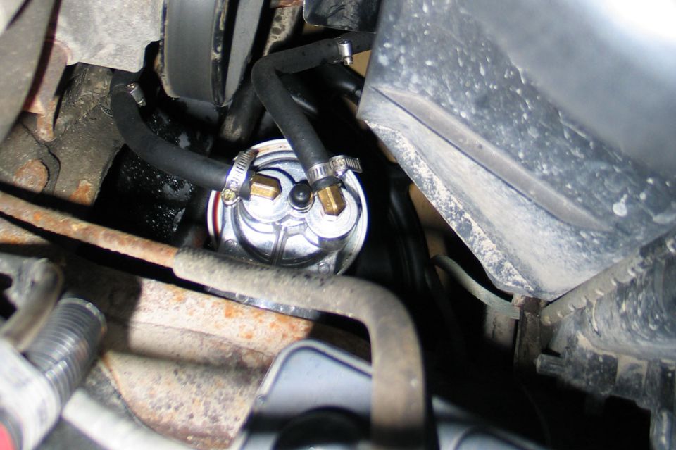 Chrome inline transmission filter with brass fittings and hose clamps under a truck