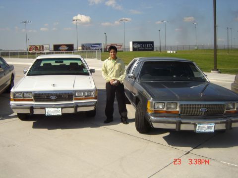 1988 Ford LTD Crown Victoria - Two 1988 Ford Crown Victoria LTDs are parked side-by-side with a man standing between them.