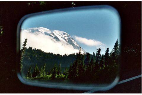 1979 Ford Bronco - A scenic view of a snow-capped mountain and forest is captured in the reflection of a vehicle's side mirror.