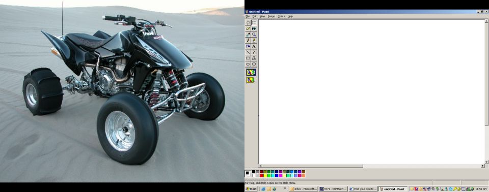 Black sport quad ATV power-sliding on sand dunes beside an open MS Paint window