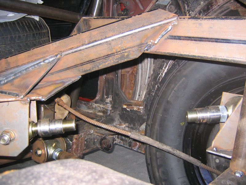 Custom rear suspension fabrication with welded metal brackets and a tire visible