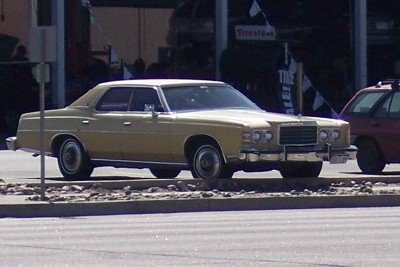 1972 Ford Ranchero - A 1973 Ford sedan is parked next to a red SUV. The Ford's grille and headlights are visible.
