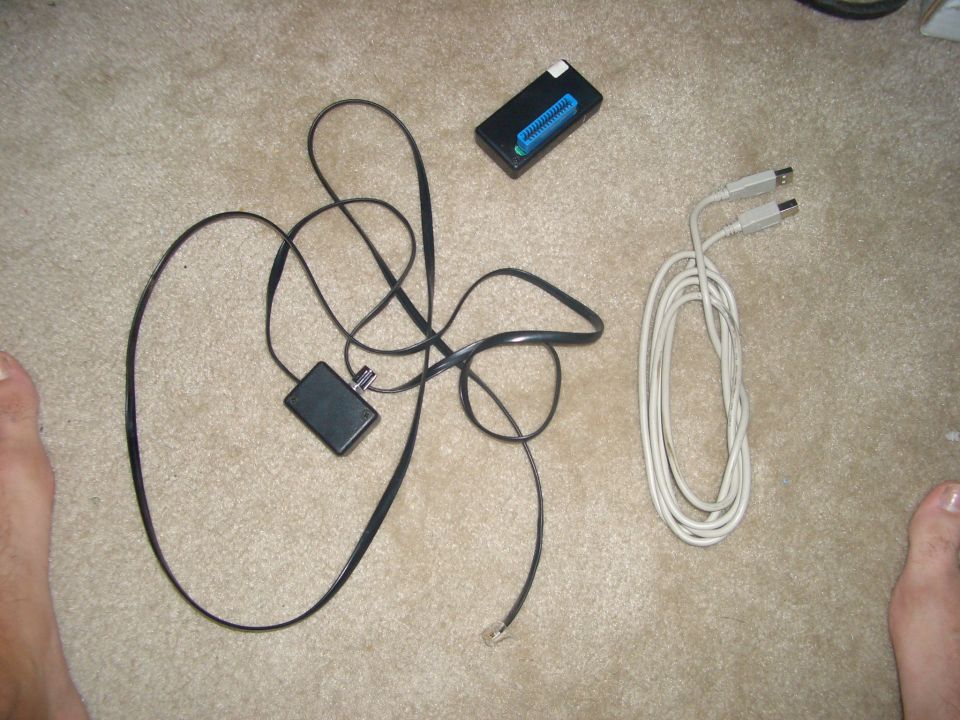 Electronic components and cables on carpet, including a black box with a blue connector and two USB cables