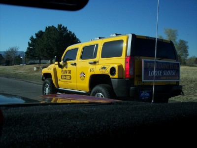 1972 Ford Ranchero - Yellow SUV taxi with casino advertisement on the rear door and taxi company branding on the side.