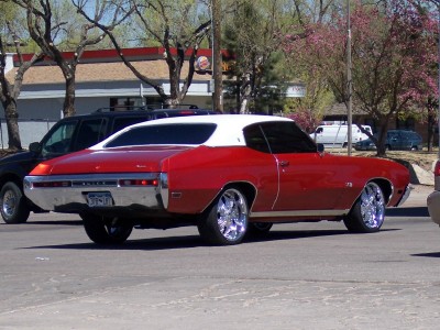 1972 Ford Ranchero - A classic red and white coupe with custom chrome wheels is seen from the rear-three-quarter view.