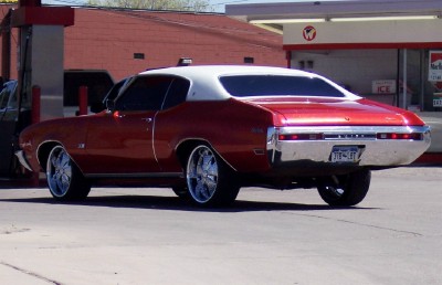 1972 Ford Ranchero - This red and white coupe has a large chrome bumper and custom wheels, suggesting a model year around 1970.