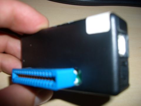 1990 Ford Bronco - A black electronic device with a blue connector is held by a hand.