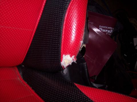 1972 Ford Ranchero - Close-up of damaged car seat upholstery, showing red and black fabric with a tear.