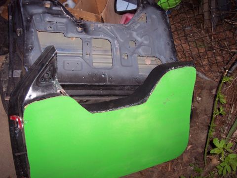 1974 Ford Bronco - A disassembled car door frame and panel, painted bright green, sits outdoors.