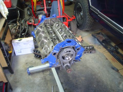 1984 Ford Bronco - Engine block on a stand in a garage setting, with a partial view of a vehicle in the background.