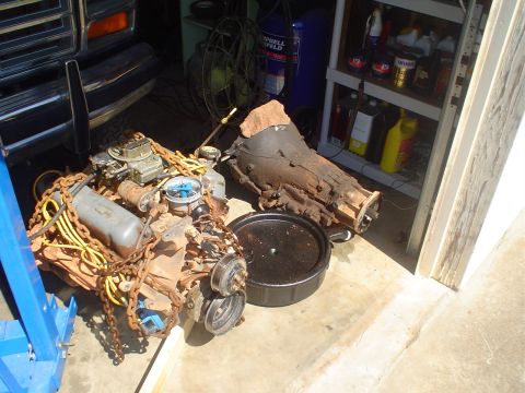 1984 Ford Bronco - A pulled small-block V8 sits on the garage floor wrapped in a lifting chain, with a four-barrel carburetor, yellow plug wires, distributor…