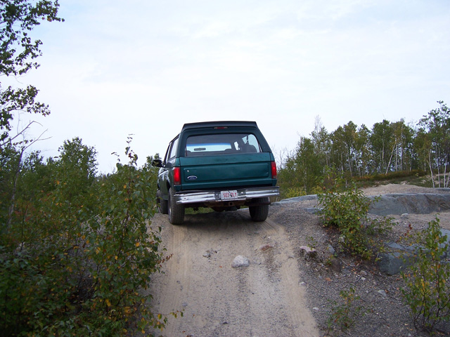 Rear view of a 1996 Ford Bronco driving on a dirt trail