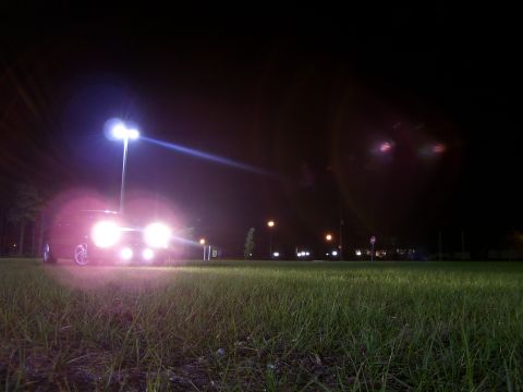 1994 Ford Probe - A car's headlights illuminate a dark, grassy field at night, creating a dramatic scene.