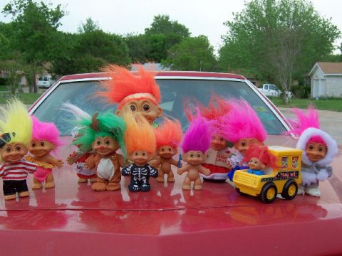 1979 Ford Ranchero - A group of troll dolls are gathered on the hood of a red vehicle, with a toy school bus among them.