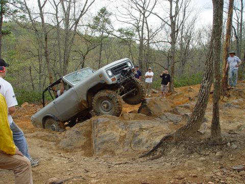 1996 Ford Bronco - Off-road vehicle attempts to climb over large rocks on a challenging trail.