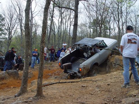 1996 Ford Bronco - Spectators watch as a modified off-road vehicle attempts to traverse a challenging rocky course.