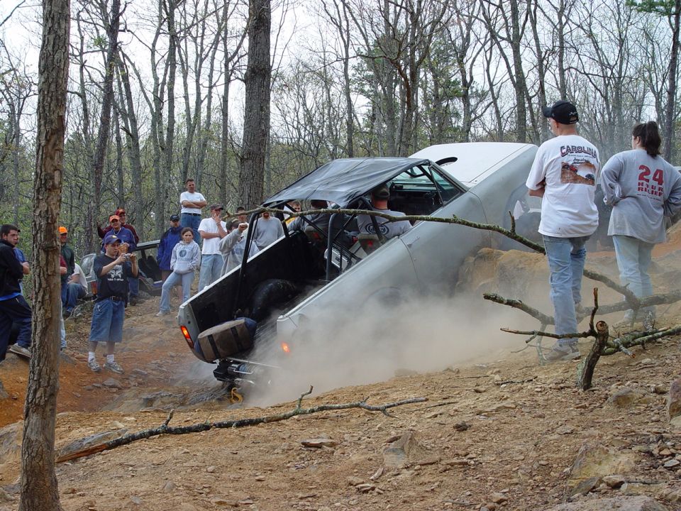 Off-road vehicle on its side in dirt, with spectators