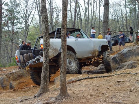 1996 Ford Bronco - Off-road vehicle navigates a rocky trail with spectators watching.