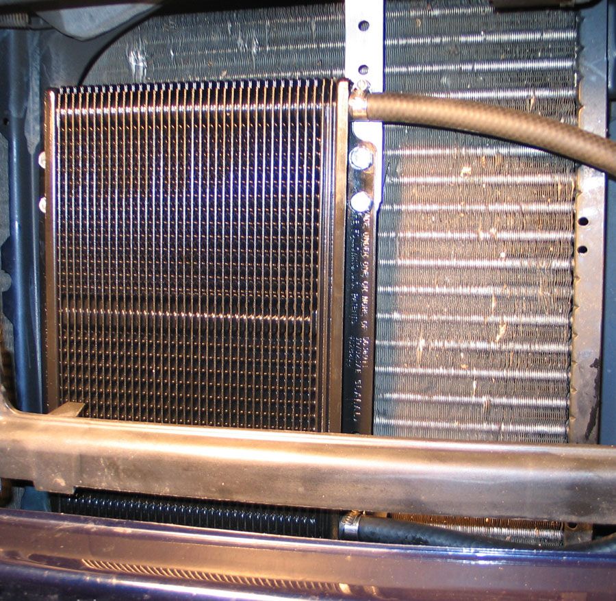 Aftermarket transmission cooler mounted ahead of radiator with strap bracket and hose