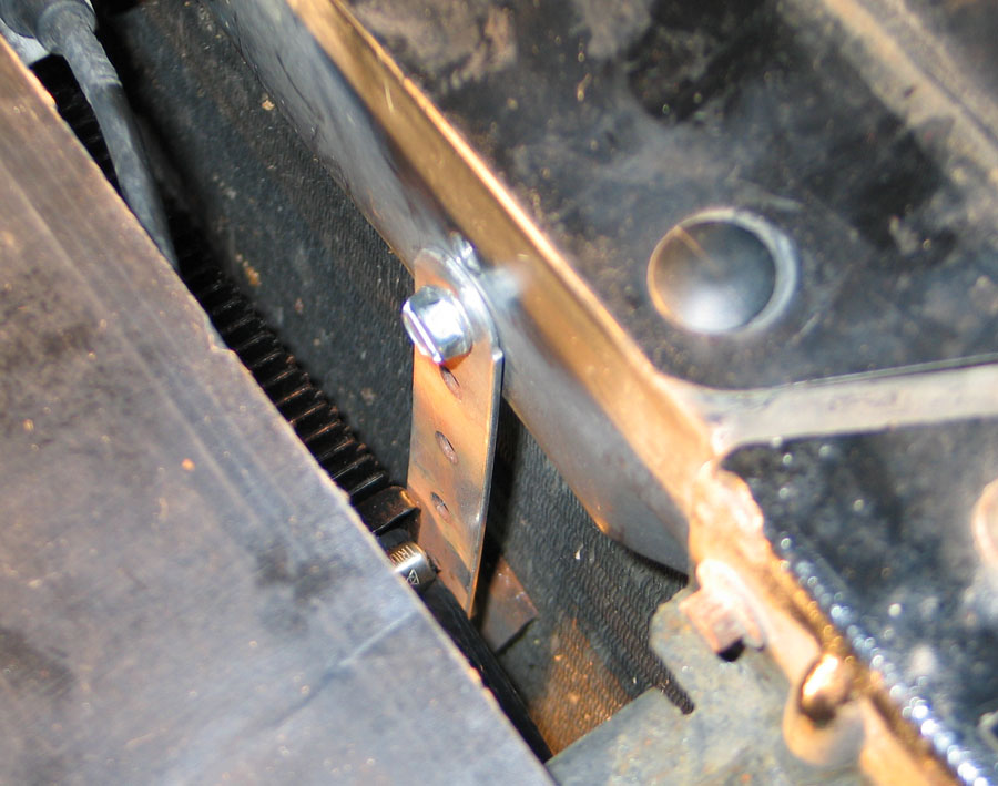 Slotted steel bracket with hex bolt securing a cooler ahead of a radiator core