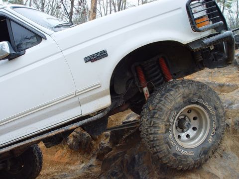 1996 Ford Bronco - This 1996 Ford Bronco is shown tackling a rocky trail, demonstrating its off-road capabilities with aggressive tires and suspension.