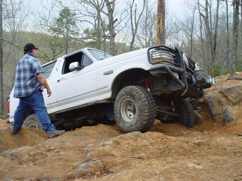 1996 Ford Bronco - A man watches as a white 1996 Ford Bronco navigates a rocky off-road course.