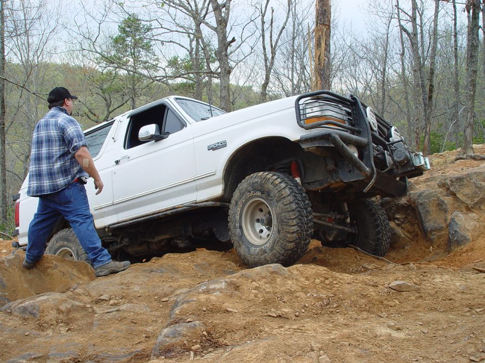 White 1996 Ford Bronco climbing over rocks on a trail