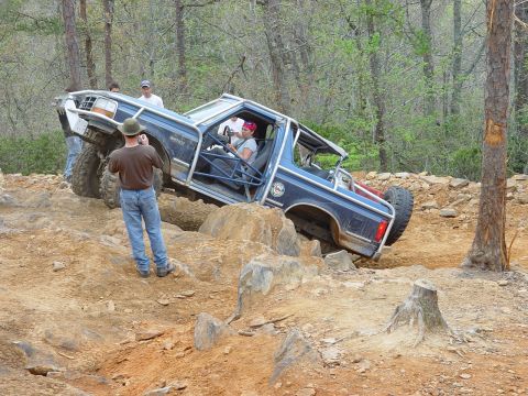 1996 Ford Bronco - This modified Bronco is tackling a challenging off-road course with a spectator capturing the action.