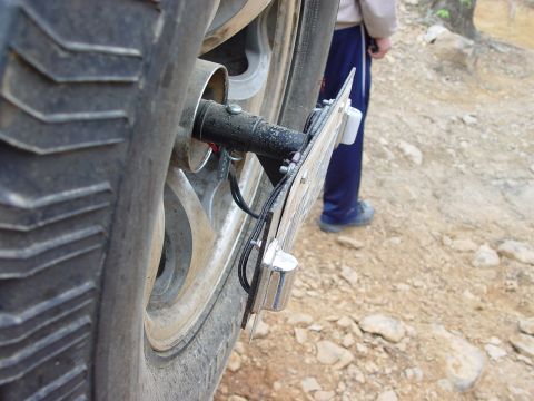 1996 Ford Bronco - Close-up view of a vehicle's rear tire and its license plate mounting hardware, with a person standing in the background.