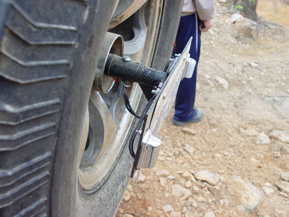 Rear tire and license plate mount with visible wiring and a person in the background