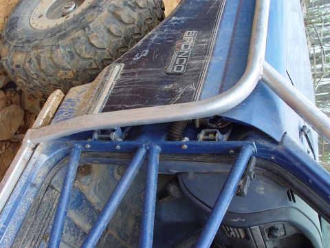 1996 Ford Bronco - The 'BRONCO' badge is visible on the side of this blue vehicle, which has a roll cage and a spare tire.