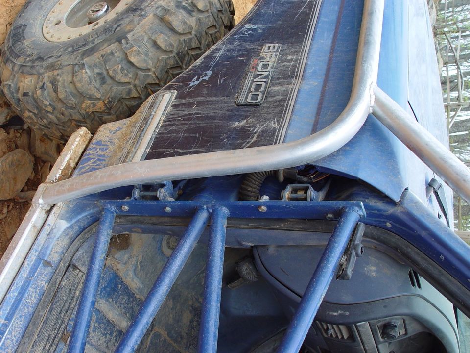 Close-up of a blue Ford Bronco fender with a roll cage and spare tire. The 'BRONCO' badge is visible