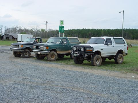 1996 Ford Bronco - Three modified Ford SUVs are parked in a line near a BP gas station.