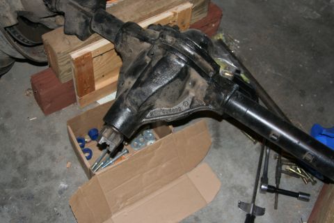 1992 Ford Bronco - A Ford Dana 44 axle assembly is shown, supported by wooden blocks, with a box of hardware nearby.