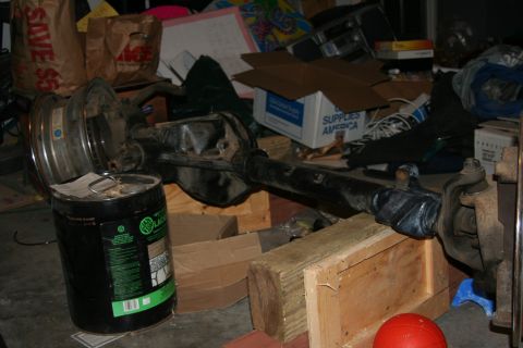 1992 Ford Bronco - Rear axle assembly, possibly from a Ford Bronco, sits in a cluttered garage setting.
