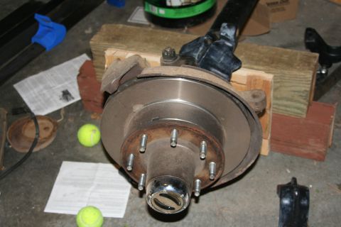 1992 Ford Bronco - A close-up view of a vehicle's axle hub and brake assembly, resting on wooden blocks.