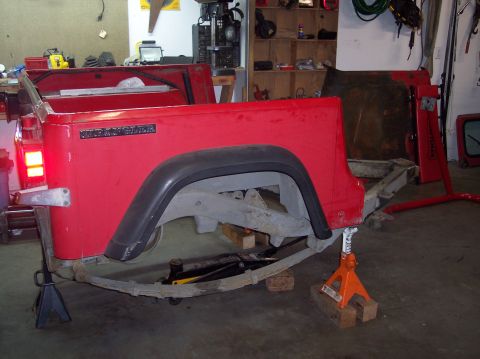 2003 Jeep TJ - The rear section of a red Jeep Wrangler is disassembled and supported by jack stands in a garage.
